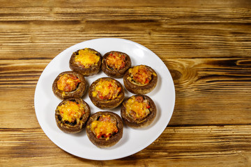 Baked mushrooms stuffed with minced meat, mushroom, paprika, onion and cheese on wooden table
