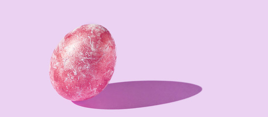 One decorative egg with hard shadow. Art easter concept. Single decorated red color. Pink background. Horizontal