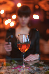 Blissful woman silhouette with a gun. In front of her is a glass of wine on the table.