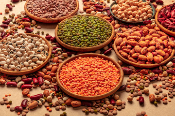 Legumes assortment on a brown background. Lentils, soybeans, chickpeas, red kidney beans, a vatiety...