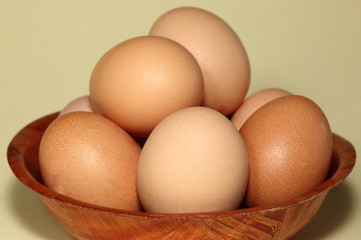 fresh eggs on wooden bowl close up on pastel color background
