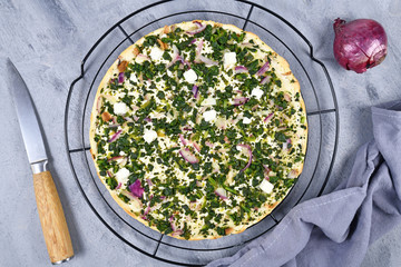 'Flammkuche' or 'Tarte Flambee', a thin pizza-like baked pie from German-French Alsace border region, vegetarian variation with spinach, red onions and feta cheese