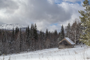 Winter landscape. Wooden hut in the middle of a snowy forest