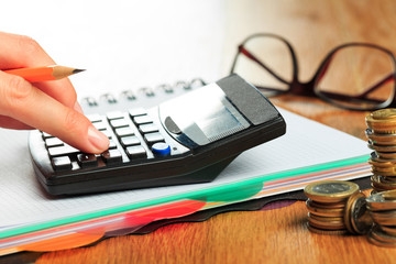 female hands working on a calculator on wooden background