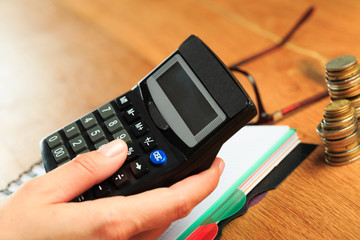 female hands working on a calculator on wooden background