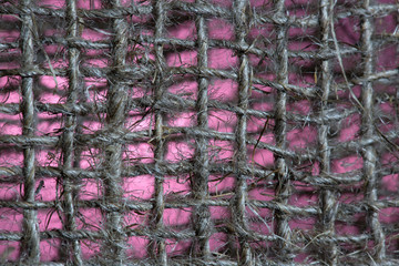 Background image of interwoven threads. Pink background Dark stripes and threads, vertical and horizontal.