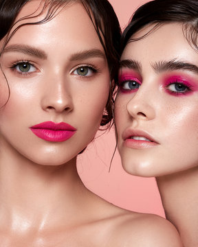 Two young girls on a pink background with pink make-up on lips and eyes. Clean skin. Natural retouching