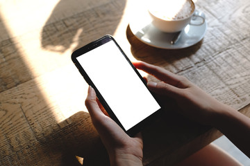 Mockup image of a woman holding and showing black mobile phone with blank screen in cafe