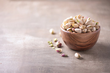 Fototapeta na wymiar Green pistachio nuts in wooden bowl on wood textured background. Copy space. Superfood, vegan, vegetarian food concept. Macro of pistachio nut texture, selective focus. Healthy snack.