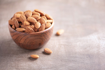 Almond nuts in wooden bowl on wood textured background. Copy space. Superfood, vegan, vegetarian...