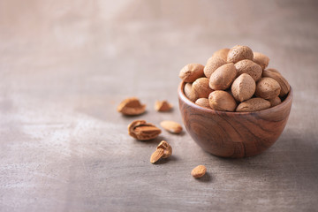 Almond nuts in wooden bowl on wood textured background. Copy space. Superfood, vegan, vegetarian food concept. Macro of almond nut texture, selective focus. Healthy snack