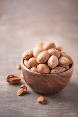Almond nuts in wooden bowl on wood textured background. Copy space. Superfood, vegan, vegetarian food concept. Macro of almond nut texture, selective focus. Healthy snack