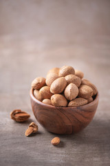 Almond nuts in wooden bowl on wood textured background. Copy space. Superfood, vegan, vegetarian food concept. Macro of almond nut texture, selective focus. Healthy snack