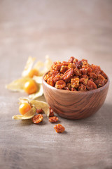 Dried physalis in wooden bowl and fresh berries on wood textured background. Copy space. Superfood, vegan, vegetarian food concept. Macro of inca berries, selective focus. Healthy snack.