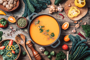 Vegan diet. Autumn harvest. Healthy, clean food and eating concept. Zero waste. Pumpkin soup with vegetarian cooking ingredients, wooden spoons, kitchen utensils on wooden background. Top view - obrazy, fototapety, plakaty