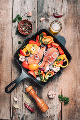 Healthy food. Dinner cooking ingredients. Raw uncooked salmon fish with vegetables, herbs, spices in iron grilling pan over wooden background. Top view, copy space