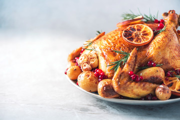 Roasted chicken with oranges, rosemary and cranberries on plate over concrete background. Traditional Thanksgiving or Friendsgiving holiday celebration dish. Friends or family dinner. Festive