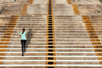 Young woman running up in urban stairs concrete background.