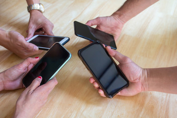 Group of young friends holding smartphone in hands having fun playing app games online together.