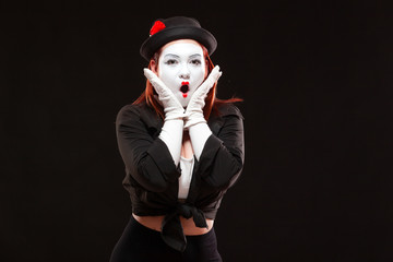 Portrait of female mime artist performing, isolated on black background. Woman opened her mouth...