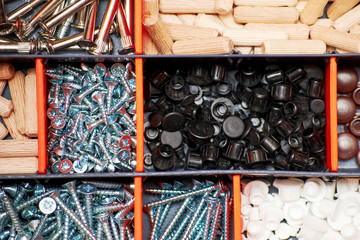Screws and dowels in the plastic toolbox. Home repair equipment. Top view. Background texture