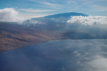 Aerial view of Mauna Kea mountain in Hawaii with rain clouds over Kohala coast and Kawaihae harbor