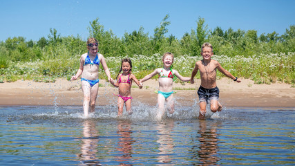 group of beautiful children runs in a wig and splashes water on a summer hot sunny day