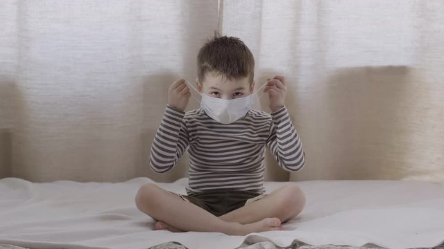 A boy taking off a medical mask from his face and becomes happy . Age 6 years. Virus protection. Precautionary measures. Slow motion
