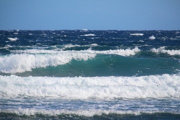 Turquoise and blue ocean waves with white foam till the horizon