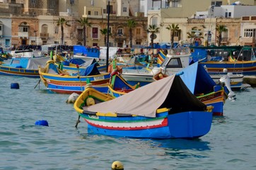 Fototapeta na wymiar Traditional eyed colorful boats Luzzu in the Harbor of Mediterranean fishing village Marsaxlokk, Malta