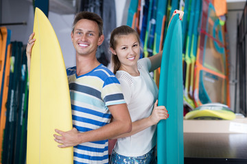 Young man and woman standing with new surfboards