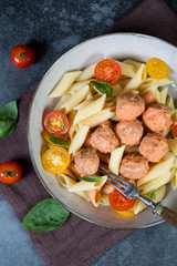 Italian Penne pasta with meatballs, tomatoes and aromatic herbs