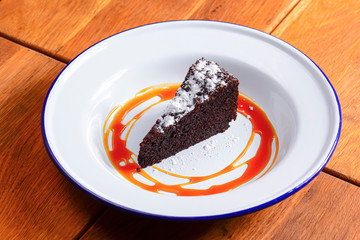A slice of delicious chocolate cake. Piece of cake on a white plate with caramel. Sweet food.