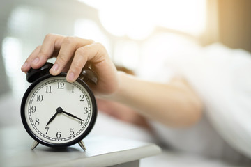 Close up of man lying in bed turning off hand reaching out for alarm clock color black Wake up late...