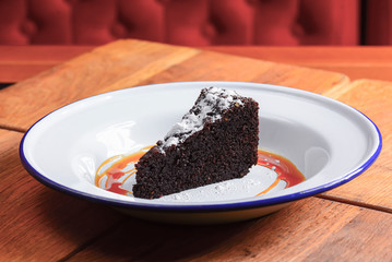 A slice of delicious chocolate cake. Piece of cake on a white plate with caramel. Sweet food.