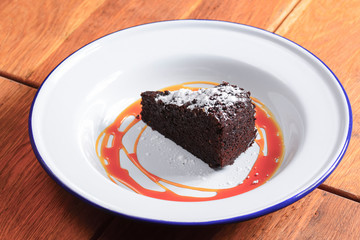 A slice of delicious chocolate cake. Piece of cake on a white plate with caramel. Sweet food.