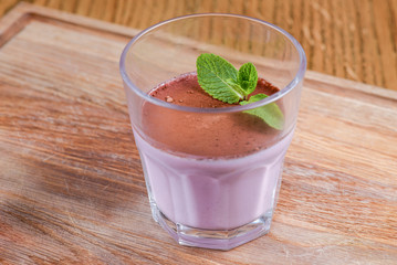 Italian panna cotta dessert with lavender and blueberry served in a glass on a wooden board over rustic wooden table.
