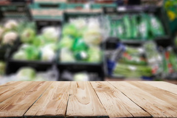 Naklejka na ściany i meble Wooden surface on blurry background of shelving with green vegetables.