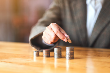 Businesswoman holding and stacking coins on the table for saving money concept