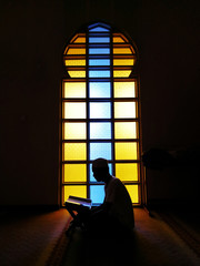 Silhouette of reading quran.Young Muslim man reading quran background.