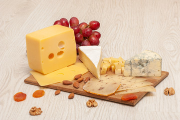 different types of cheese on a wooden board. Top view