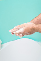 Fototapeta premium wash your hands with disinfectant soap during a coronavirus infection. close-up of a hand in soap foam. antibacterial treatment of the hands. on a blue background