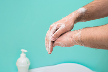 Fototapeta premium wash your hands with disinfectant soap during a coronavirus infection. close-up of a hand in soap foam. antibacterial treatment of the hands. on a blue background