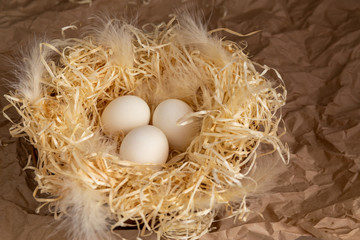 Chicken eggs lie on a wicked paper straw in a wicker basket