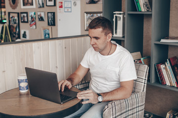 a guy in a white t-shirt is sitting with laptops in a cafe