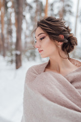 a beautiful girl in a wedding dress stands in a winter pine forest