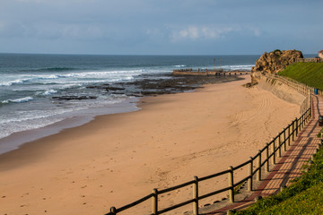 Fototapeta na wymiar Wood Fence Separates the Sand and Walkway at Beach