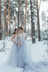 a beautiful girl in a wedding dress stands in a winter pine forest