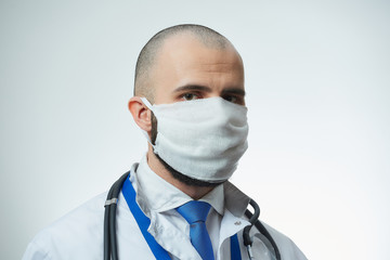 A close portrait of a doctor in a protective face mask. A doctor in a white lab coat with a stethoscope. 