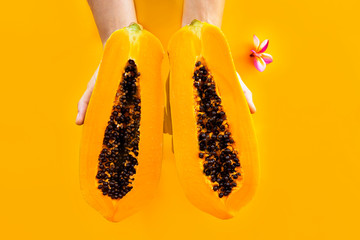 Exotic, sweet papaya fruit close-up in hands on an orange background. cutaway pawpaw. melon tree,...